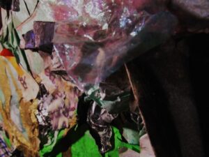 Primer plano de una composición abstracta con fragmentos de papeles arrugados, colores brillantes y texturas plásticas superpuestas, que evocan hojas y materiales naturales.