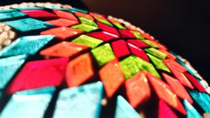 Primer plano de una decoración colorida con piezas geométricas brillantes rojas, verdes, azules y naranjas sobre fondo negro.