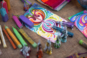 Materiales de arte vibrantes como velas de cera de colores y dibujos abstractos sobre tela de arpillera en un taller creativo.